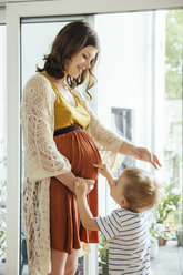 Kleiner Junge zeigt auf den Bauch seiner schwangeren Mutter zu Hause - MFF001797