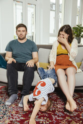 Disturbed family portrait on a sofa at home with son jumping away - MFF001799