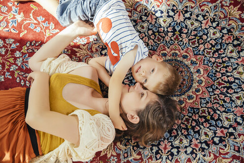 Mutter und kleiner Sohn kuscheln zu Hause auf einem Perserteppich - MFF001801