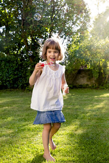 Kleines Mädchen spielt mit Seifenblasen in einem Garten - LVF003611