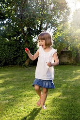 Kleines Mädchen spielt mit Seifenblasen in einem Garten - LVF003635