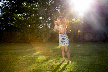 Mädchen bläst Seifenblasen in einem Garten - LVF003612