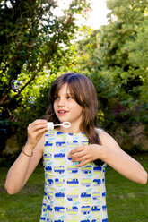 Girl blowing soap bubbles in a garden - LVF003614