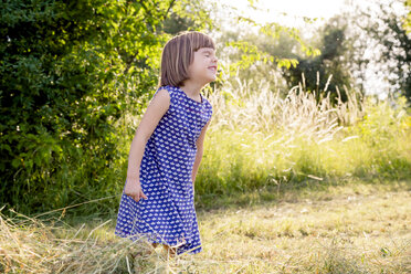 Little girl standing in hay field with closed eyes - LVF003630