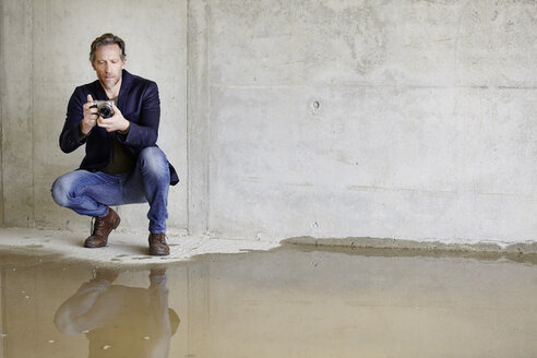 Man with camera on construction site in unfinished building - FMKF001580