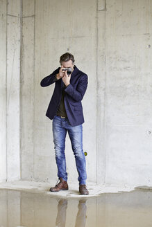 Man taking picture on construction site in unfinished building - FMKF001581