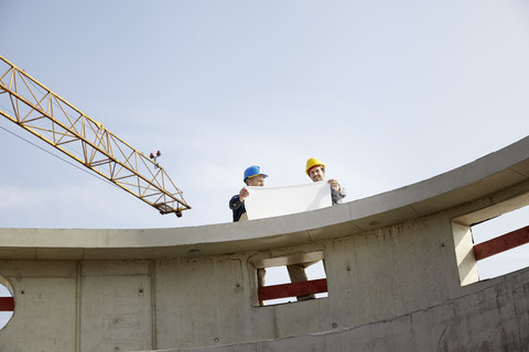 Zwei Männer auf einer Baustelle besprechen einen Bauplan, lizenzfreies Stockfoto