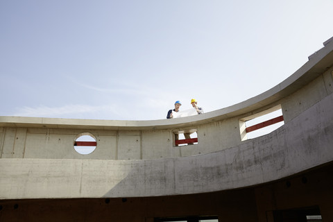 Two men on construction site discussing construction plan stock photo