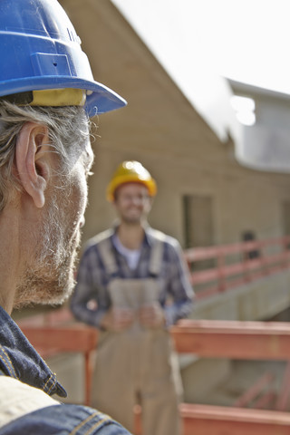 Zwei Männer mit Schutzhelmen auf einer Baustelle, lizenzfreies Stockfoto