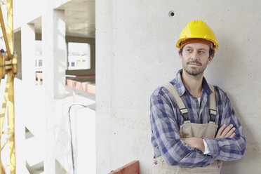 Mann mit Schutzhelm auf einer Baustelle denkt nach - FMKF001595