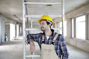 Man with hard hat on construction site thinking - FMKF001597