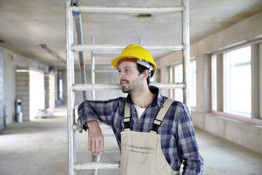 Mann mit Schutzhelm auf einer Baustelle denkt nach - FMKF001597