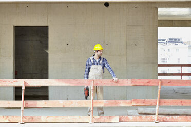 Mann mit Schutzhelm auf einer Baustelle an einem Geländer stehend - FMKF001598