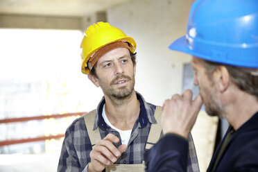 Construction worker and architect on construction site discussing - FMKF001600