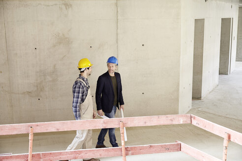 Construction worker and architect talking on construction site - FMKF001606