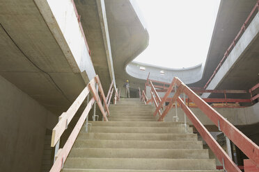 Mann mit Schutzhelm auf einer Baustelle an einer Treppe stehend - FMKF001610