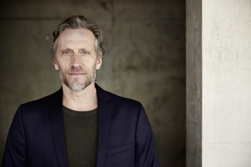 Portrait of confident mature man at concrete wall - FMKF001615