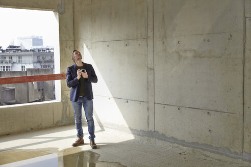 Man with camera on construction site in unfinished building - FMKF001623