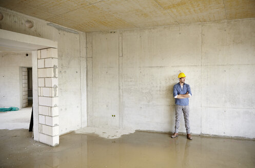 Man on construction site standing at large puddle - FMKF001627