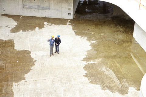 Two men with hard hats talking on construction site stock photo