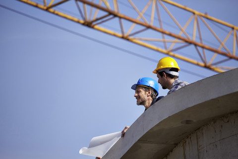 Two men on construction site with construction plan stock photo