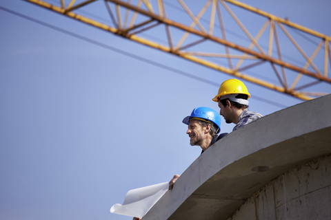 Zwei Männer auf einer Baustelle mit Bauplan, lizenzfreies Stockfoto