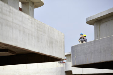 Zwei Männer auf einer Baustelle mit Schutzhelmen - FMKF001636