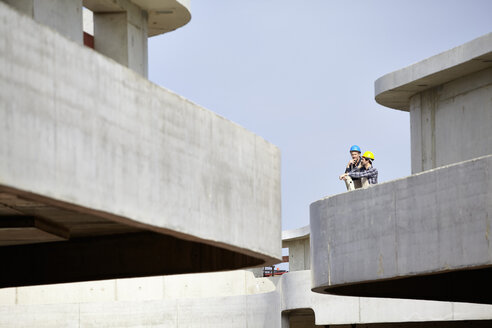 Zwei Männer auf einer Baustelle mit Schutzhelmen - FMKF001636