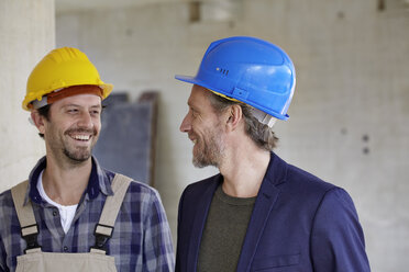 Lächelnder Bauarbeiter und Architekt auf einer Baustelle - FMKF001638