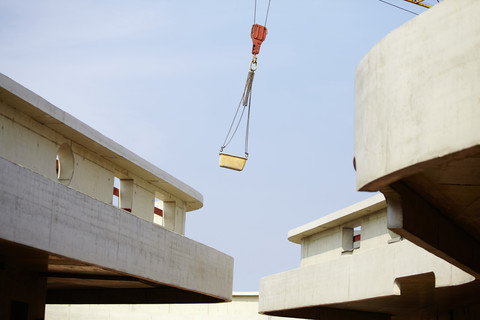 Kran hebt Container auf einer Baustelle, lizenzfreies Stockfoto