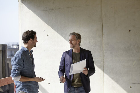 Two men talking on construction site - FMKF001653