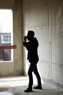 Man with hard hat taking picture on construction site in unfinished building - FMKF001654