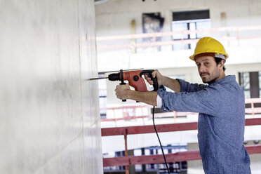 Man with hard hat on construction site using drill - FMKF001662