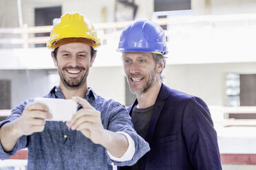 Two men on construction site taking a selfie - FMKF001666