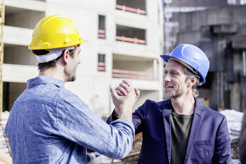 Two men on construction site shaking hands stock photo