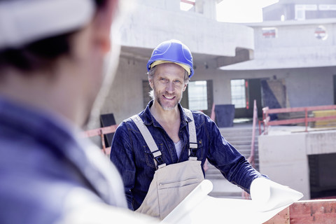 Two workers on construction site with construction plan stock photo