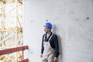 Arbeiter auf einer Baustelle an einer Betonwand stehend - FMKF001681