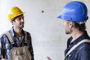 Zwei Bauarbeiter auf einer Baustelle im Gespräch - FMKF001683