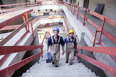 Zwei Bauarbeiter auf einer Baustelle, die eine Treppe hinaufgehen, lizenzfreies Stockfoto