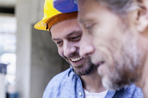 Nahaufnahme von zwei lächelnden Männern auf einer Baustelle - FMKF001688