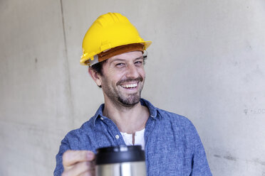 Glücklicher Mann auf einer Baustelle bei einer Kaffeepause - FMKF001698