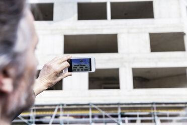 Mann fotografiert auf einer Baustelle - FMKF001702