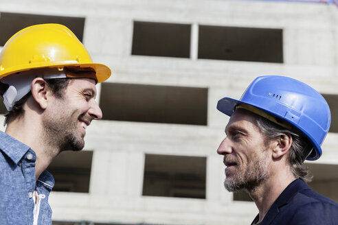 Zwei Männer auf einer Baustelle mit Schutzhelmen - FMKF001706