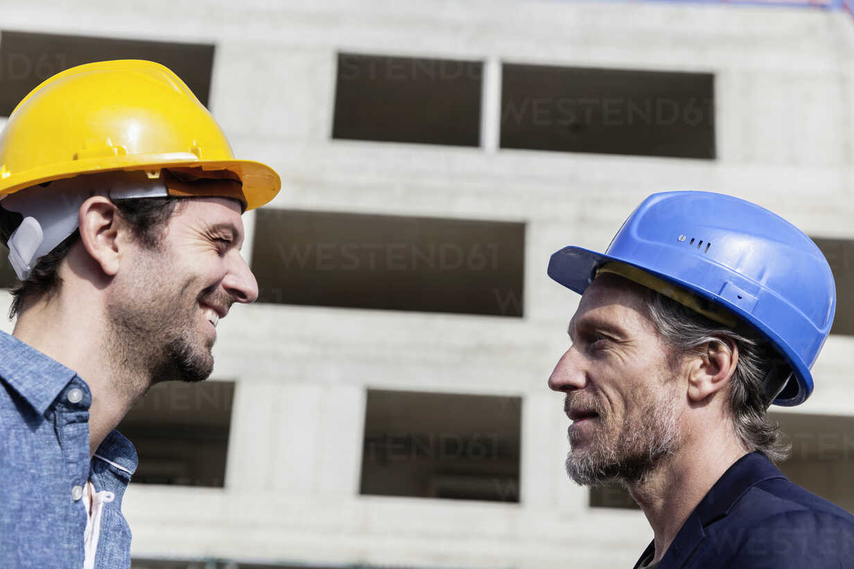 Two men on construction site wearing hard hats stock photo