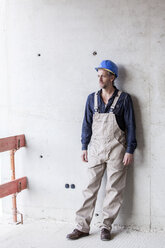 Worker on construction site standing at concrete wall - FMKF001708