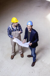 Bauarbeiter und Architekt mit Plan im Gespräch auf der Baustelle - FMKF001845