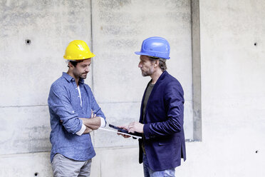 Two men on construction site wearing hard hats - FMKF001733
