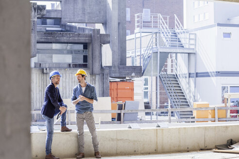 Zwei Männer auf einer Baustelle mit Schutzhelmen - FMKF001717