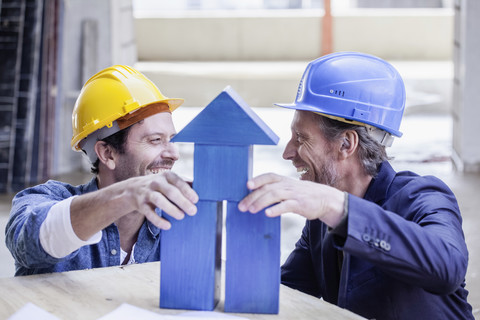 Two happy men with hard hats and model house stock photo