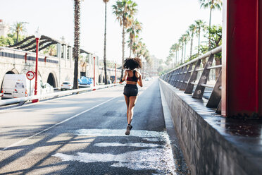 Spain, Barcelona, back view of jogging young woman on a street - EBSF000710